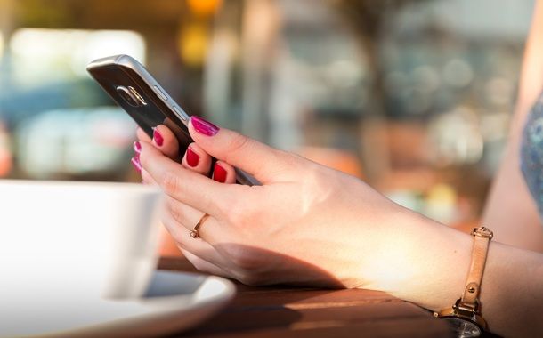 Una donna che usa il suo smartphone al bar