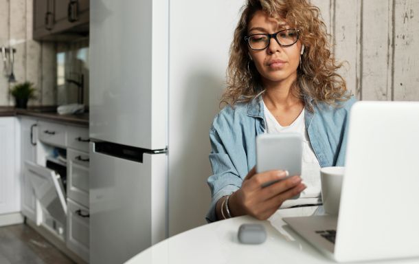 persona con PC e smartphone in cucina