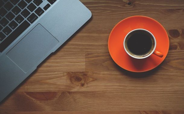 Un computer con accanto una tazza di caffè