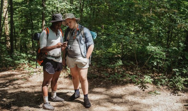 escursionisti in un bosco con smartphone