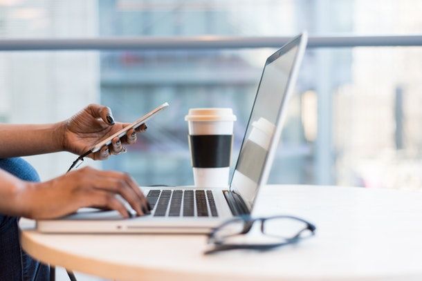 persona che usa il computer con un telefono in mano